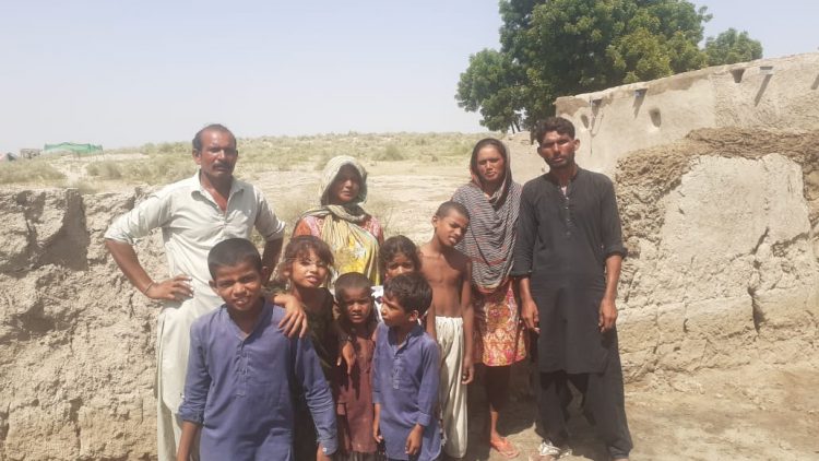 Asif George with his family at their damaged houses in the flooded Chak village